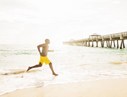 Mixed race barefoot man running on beach