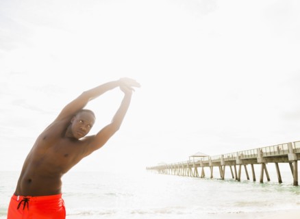 Mixed race man stretching on beach
