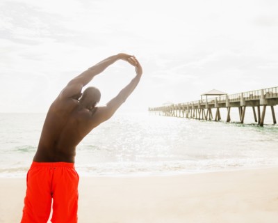 Mixed race man stretching on beach