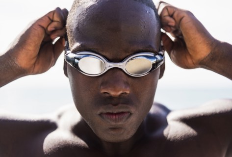 Mixed race swimmer putting on goggles