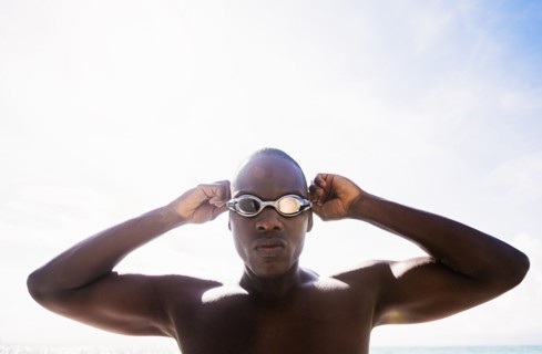 Mixed race swimmer putting on goggles