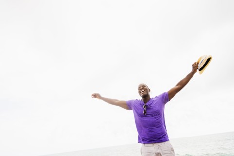 Mixed race man with arms outstretched on beach
