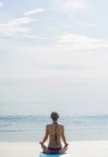 Caucasian woman meditating on beach