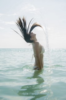 Caucasian woman splashing hair in ocean