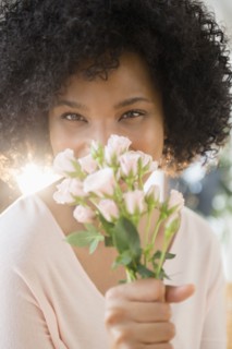 Woman smelling bouquet of roses indoors