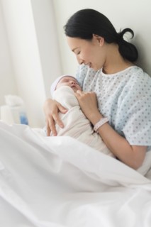 Asian mother holding newborn baby in hospital bed