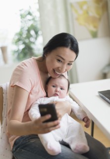 Asian mother and baby taking selfie in home office