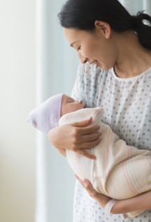 Asian mother holding newborn baby in hospital