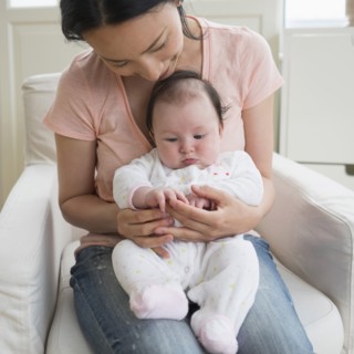 Asian mother playing with baby in living room