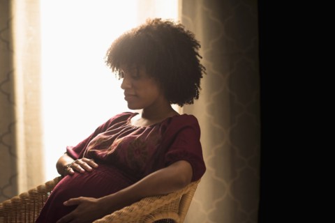 Pregnant African American mother holding her stomach
