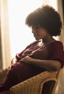 Pregnant African American mother holding her stomach