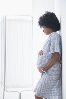 Pregnant African American mother holding stomach in hospital