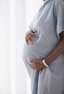 Pregnant African American mother holding her belly in hospital