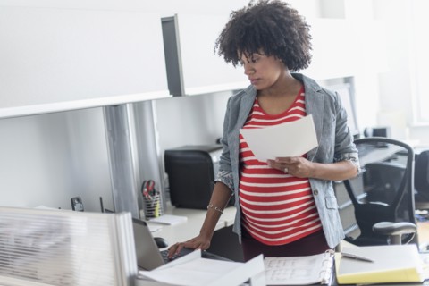 Pregnant African American businesswoman working in office