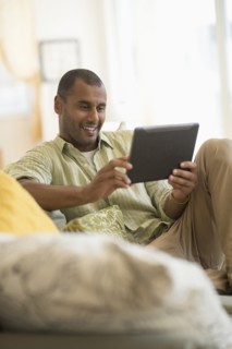 Mixed race man using digital tablet in living room