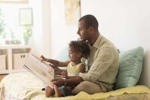 Father and daughter reading book on bed