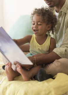 Father and daughter reading book on bed