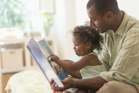 Father and daughter reading book on bed