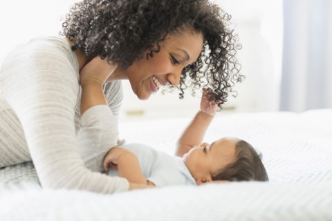 Mixed race mother holding baby on bed