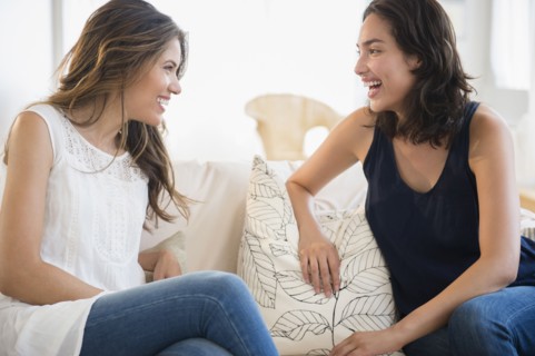 Hispanic women talking on sofa