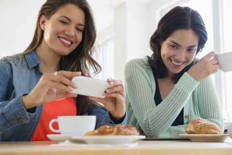 Hispanic women taking cell phone photograph of breakfast