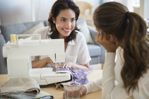 Hispanic women using sewing machine in living room