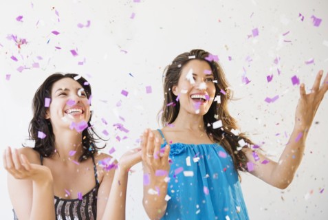 Hispanic women throwing confetti at party