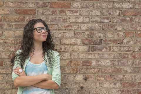 Pensive mixed race woman standing with arms crossed