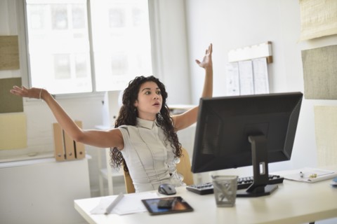 Mixed race businesswoman frustrated at computer at desk in office