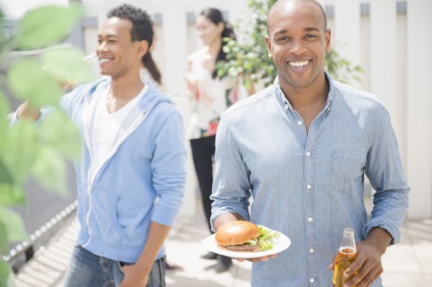 Man having beer and burger at backyard barbecue