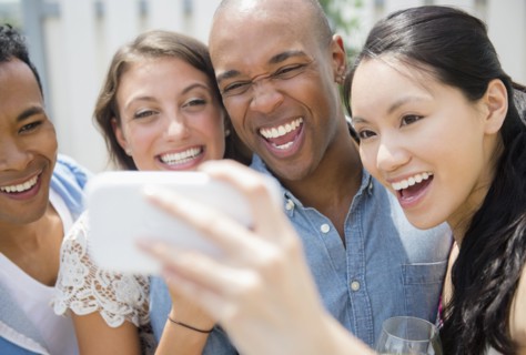 Friends taking cell phone photograph at party