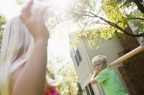 Caucasian children playing baseball in backyard