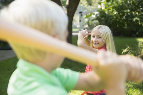 Caucasian children playing baseball in backyard