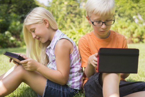 Caucasian children using digital tablets in backyard