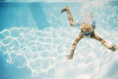 Caucasian boy swimming underwater in pool