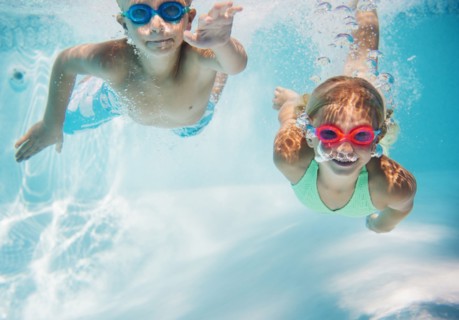 Caucasian children swimming underwater in pool