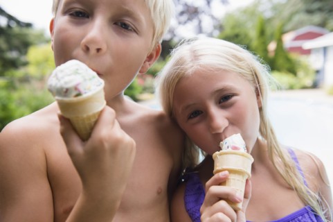 Caucasian children eating ice cream near swimming pool