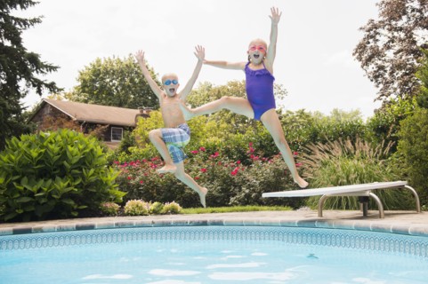Caucasian children jumping into swimming pool