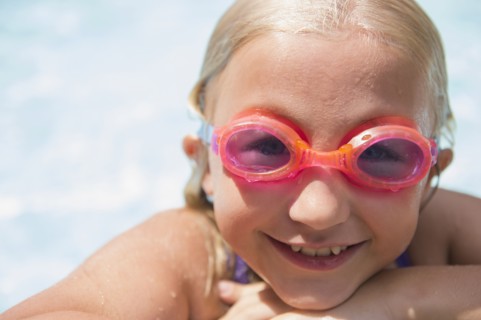 Caucasian girl wearing goggles in swimming pool