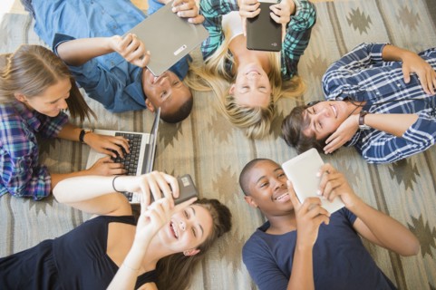Teenagers laying on floor using technology