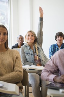 Teenage student raising hand in classroom