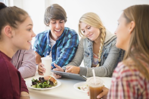 Teenagers using digital tablet at table