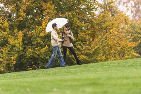 Couple walking with umbrella in park