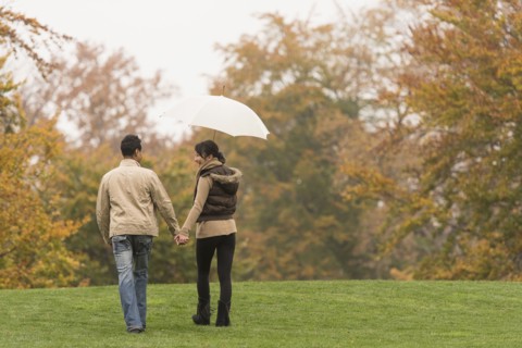 Couple walking with umbrella in park