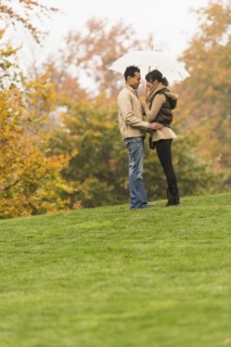 Couple standing with umbrella in park