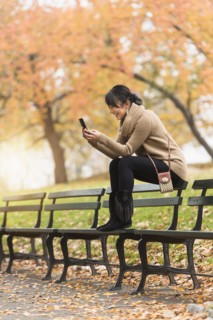 Asian woman using cell phone on park bench