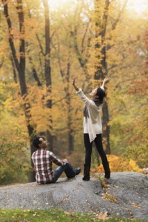 Woman cheering with arms outstretched near boyfriend in park