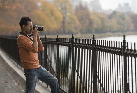 Mixed race man taking photograph on waterfront
