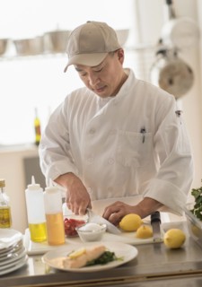 Korean chef slicing food in kitchen
