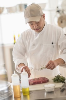 Korean chef seasoning meat in kitchen